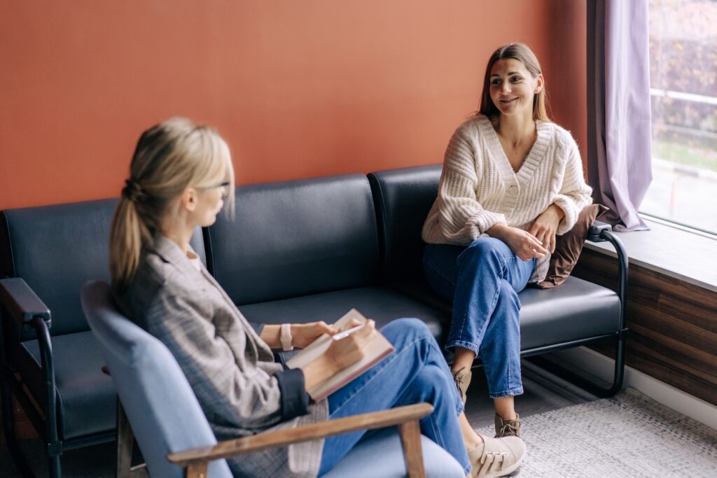 A smiling woman talks to a professional coach about mental health and development.